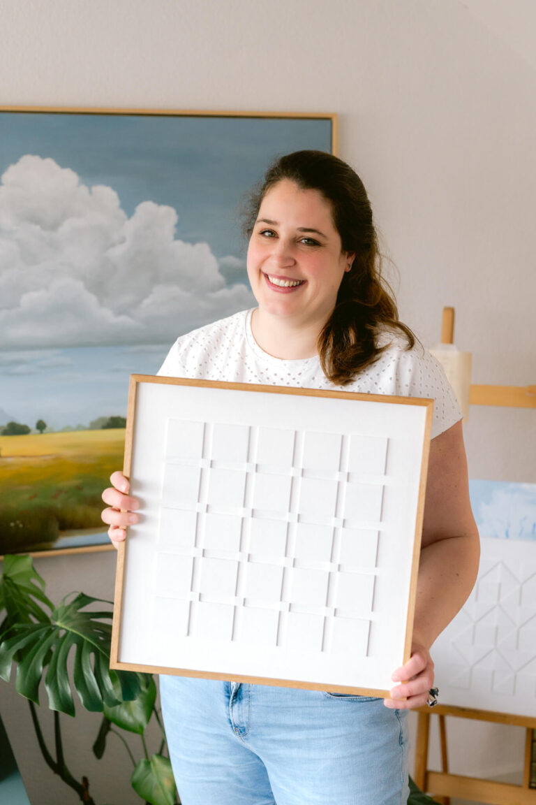 Foto van Aniek van Atelier Hemelsblauw. Ze houdt een kunstwerk vast.